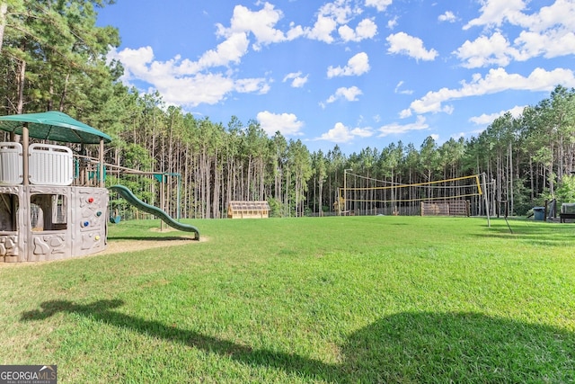 exterior space with a yard, a wooded view, and volleyball court