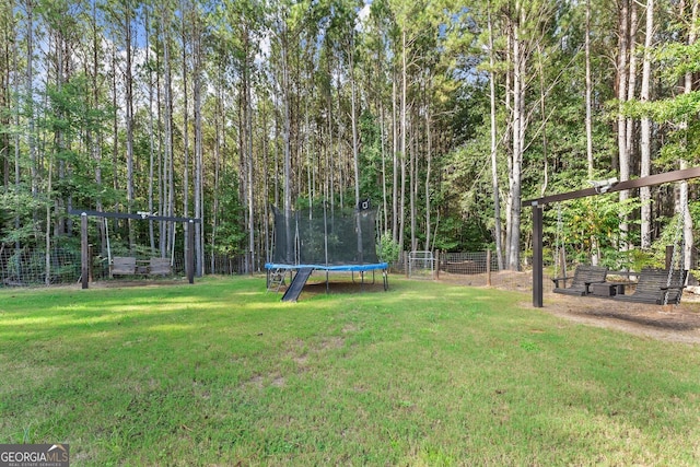 view of yard featuring a trampoline and fence