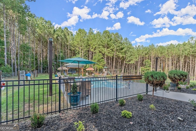 pool with a yard, a patio area, fence, and a view of trees