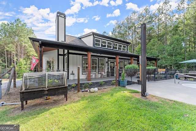 view of front of home with a patio, a chimney, a front lawn, and fence