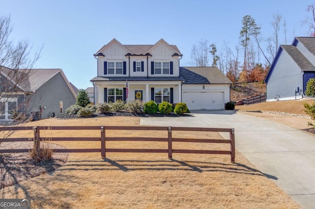 view of front facade with a garage, a fenced front yard, board and batten siding, and concrete driveway