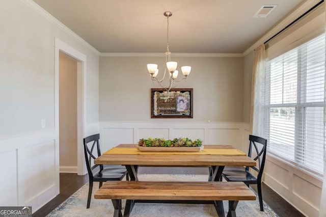 dining room with a chandelier, ornamental molding, and wood finished floors