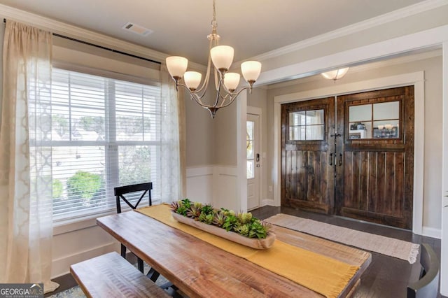 dining area with a notable chandelier, visible vents, a decorative wall, ornamental molding, and wainscoting