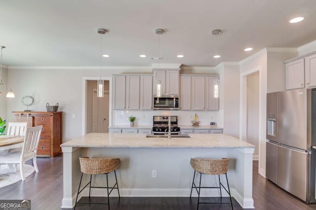 kitchen with appliances with stainless steel finishes, dark wood-type flooring, a sink, and a kitchen breakfast bar