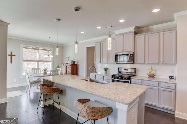 kitchen featuring dark wood-style flooring, stainless steel appliances, backsplash, a sink, and a kitchen bar