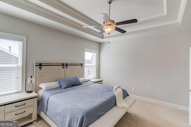 bedroom with a raised ceiling, light colored carpet, ornamental molding, ceiling fan, and baseboards