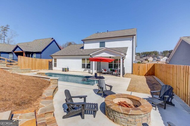 rear view of property featuring a fenced in pool, an outdoor fire pit, a fenced backyard, and a patio