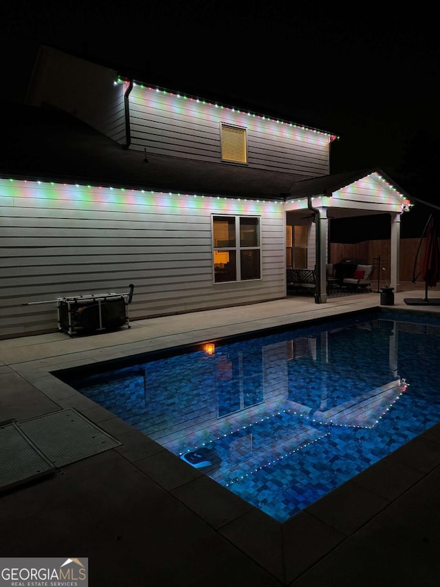 pool at twilight with a fenced in pool and a patio area