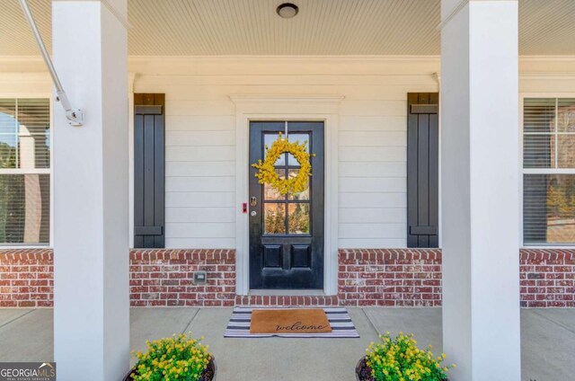 property entrance featuring covered porch and brick siding