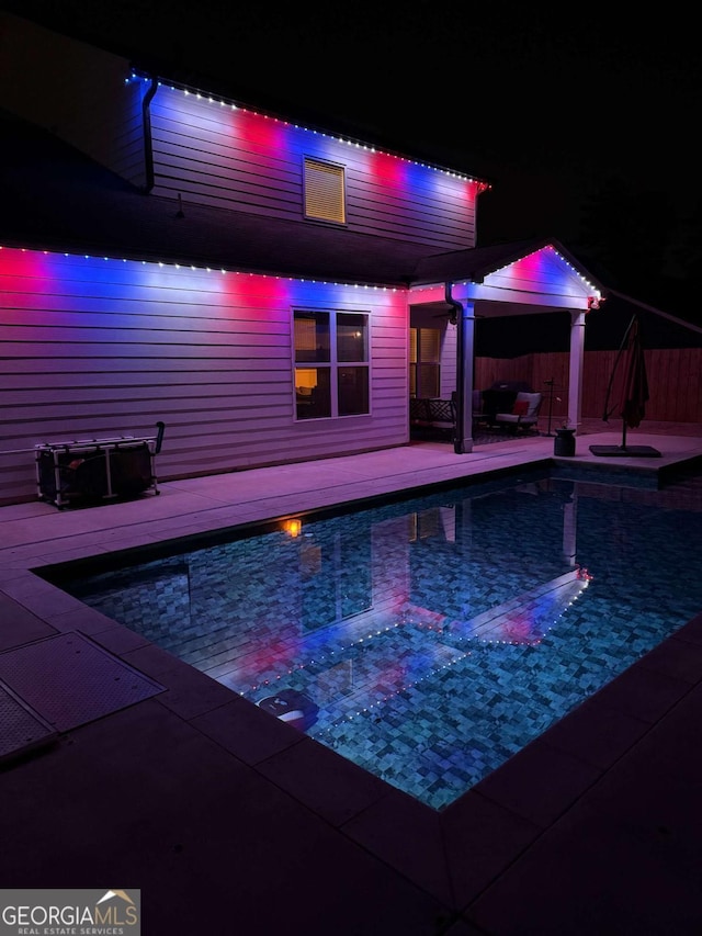 pool at twilight featuring a patio, fence, and a fenced in pool