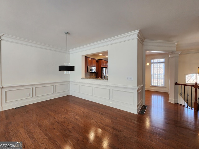 unfurnished living room featuring dark wood-style floors, visible vents, and ornate columns