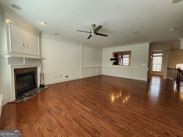 unfurnished living room with a decorative wall, wood finished floors, a high end fireplace, and crown molding