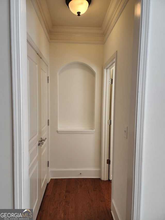 hallway with dark wood finished floors, crown molding, and baseboards