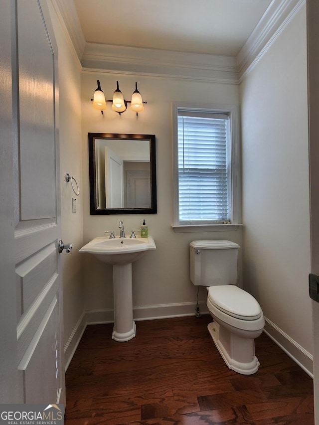 half bathroom with ornamental molding, wood finished floors, toilet, and baseboards