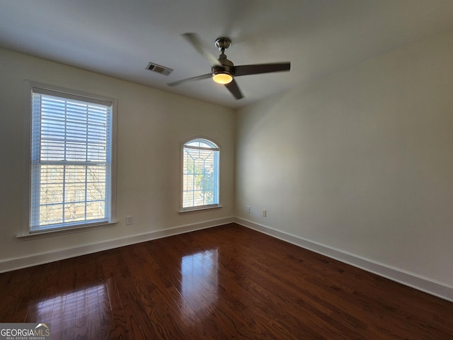 empty room with ceiling fan, baseboards, visible vents, and dark wood finished floors