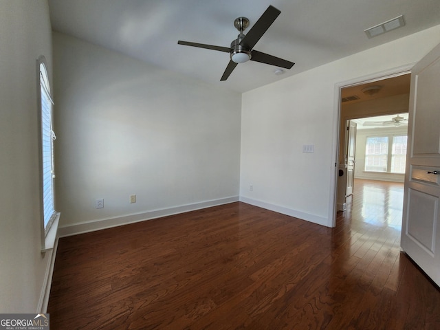 spare room with ceiling fan, dark wood-type flooring, visible vents, and baseboards