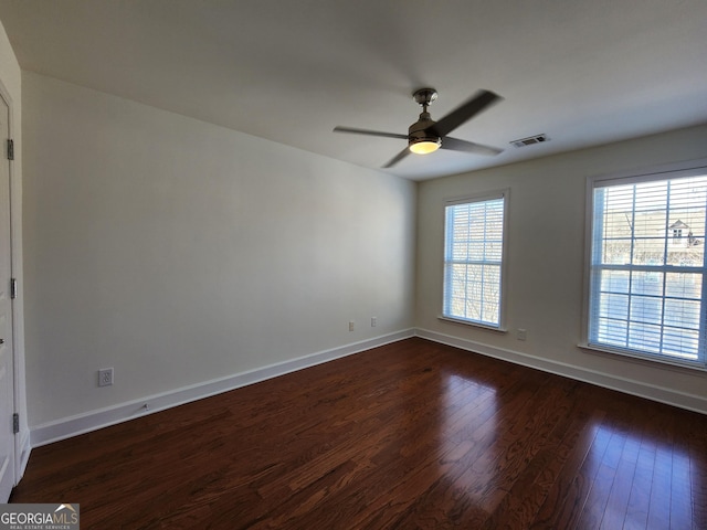 unfurnished room with a ceiling fan, dark wood-style flooring, visible vents, and baseboards