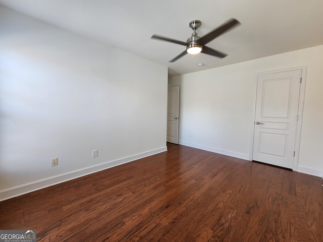 spare room featuring dark wood finished floors, a ceiling fan, and baseboards