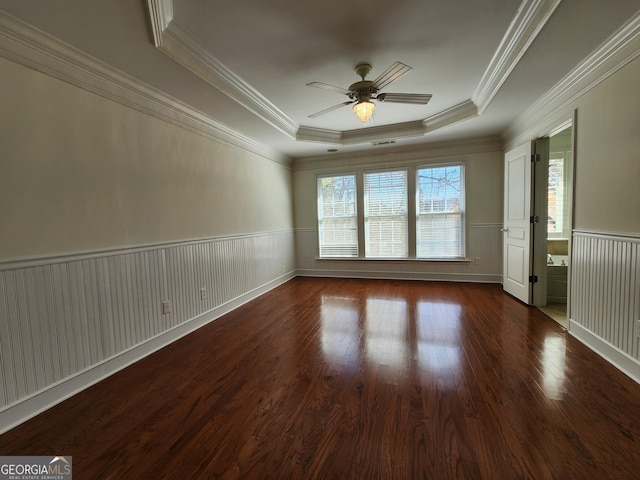 unfurnished room featuring visible vents, wainscoting, ceiling fan, wood finished floors, and a tray ceiling