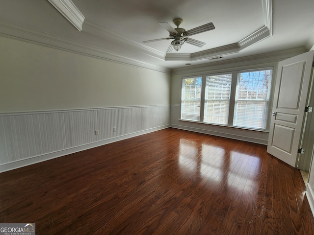 unfurnished room featuring a tray ceiling, a wainscoted wall, crown molding, a ceiling fan, and hardwood / wood-style floors