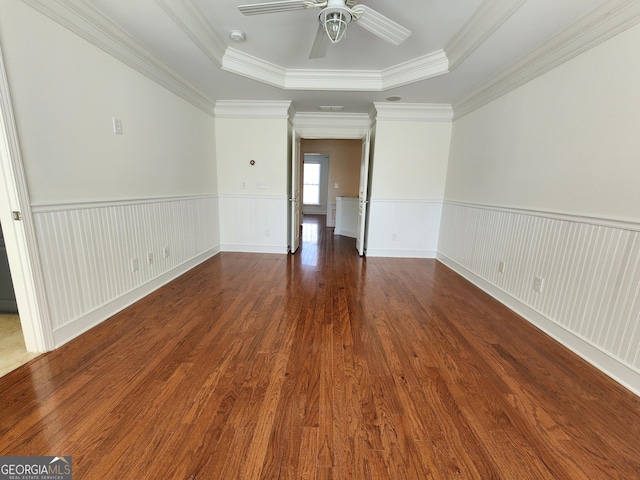 spare room featuring crown molding, a raised ceiling, wainscoting, ceiling fan, and wood finished floors