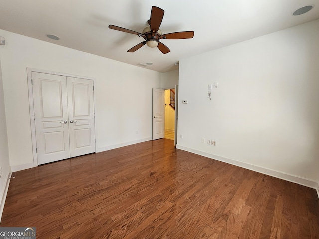 unfurnished bedroom with a closet, wood finished floors, a ceiling fan, and baseboards