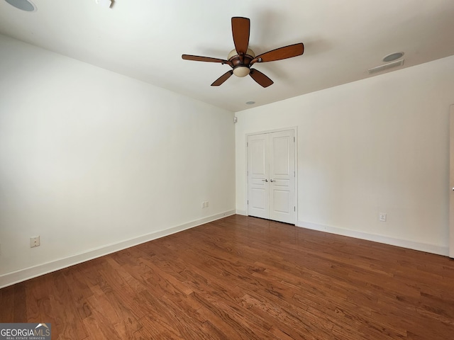 empty room with visible vents, baseboards, ceiling fan, and dark wood-type flooring