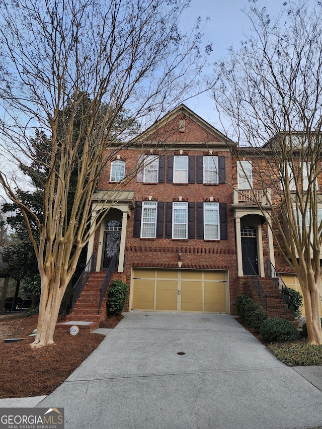 multi unit property with driveway, an attached garage, and brick siding