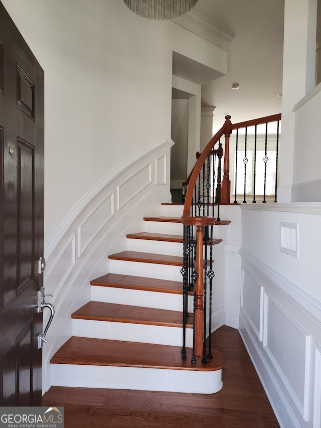 staircase with a wainscoted wall, a decorative wall, and wood finished floors