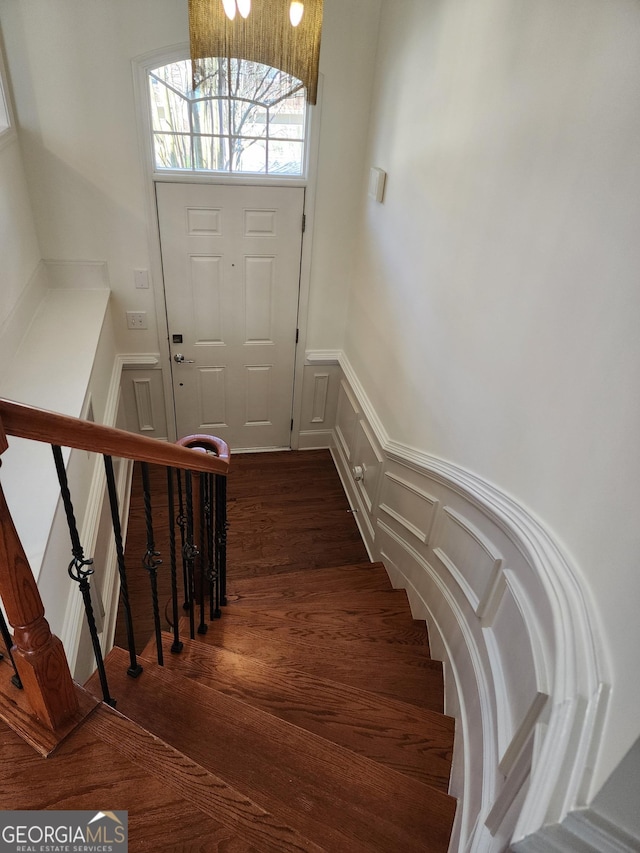 stairs with a wainscoted wall, a decorative wall, and wood finished floors