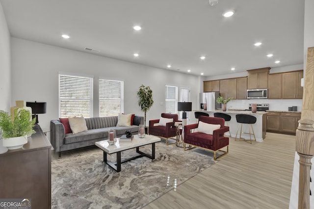 living room with light wood-style floors, visible vents, and recessed lighting