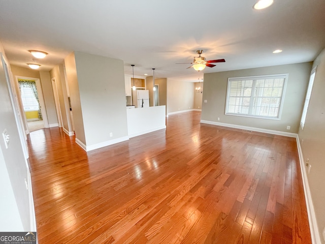 unfurnished living room with light wood finished floors, recessed lighting, a ceiling fan, and baseboards