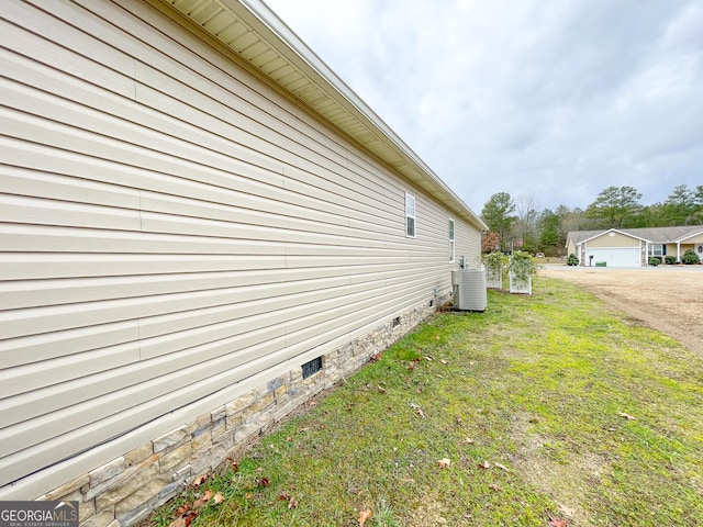 view of side of property featuring a yard, central AC unit, and crawl space