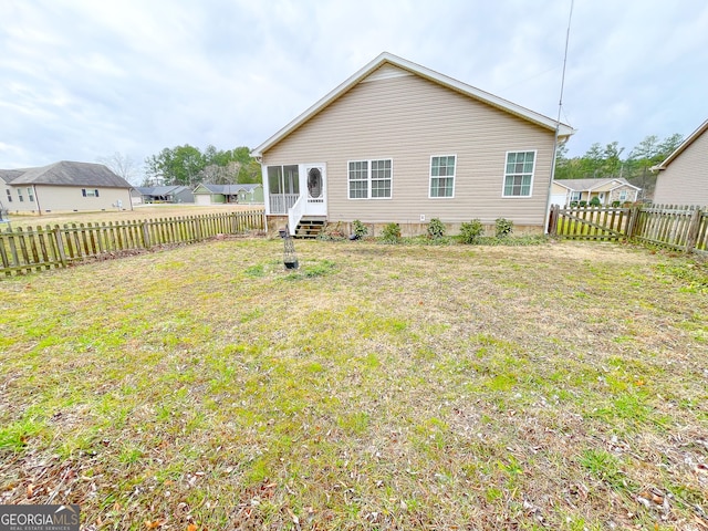 back of house featuring a sunroom, a fenced backyard, and a lawn