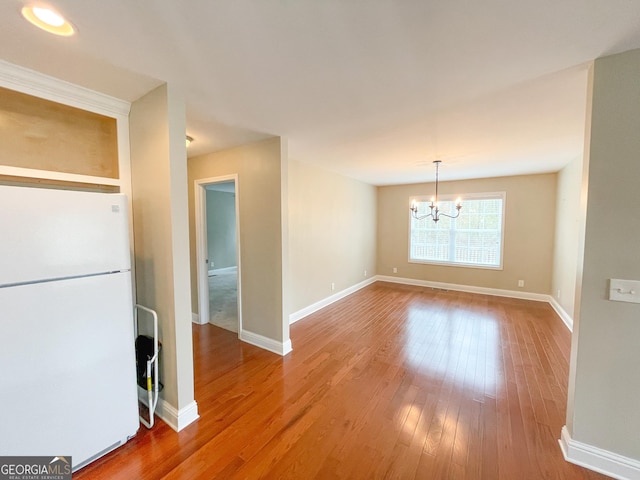 unfurnished dining area featuring a chandelier, baseboards, and hardwood / wood-style flooring