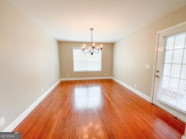 unfurnished dining area with a chandelier, baseboards, and light wood finished floors