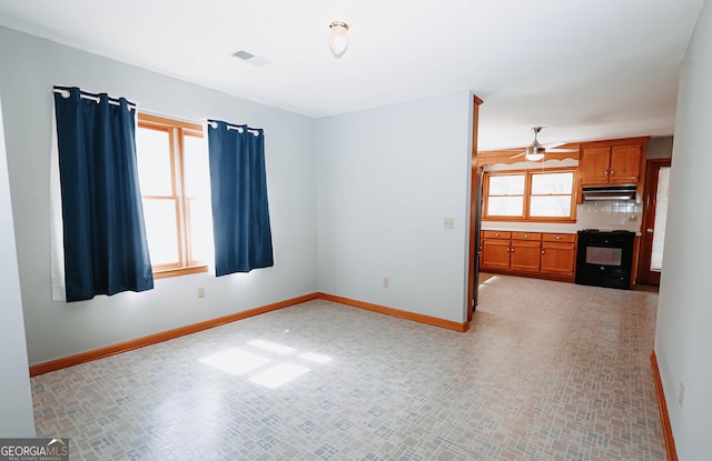 interior space with baseboards, visible vents, under cabinet range hood, and black stove