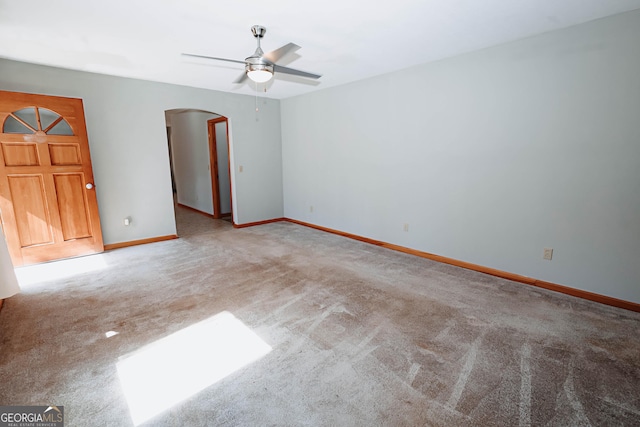 unfurnished room featuring carpet floors, arched walkways, ceiling fan, and baseboards