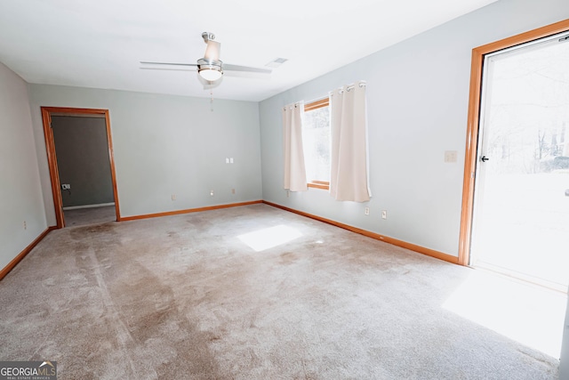 carpeted empty room featuring visible vents, a ceiling fan, and baseboards