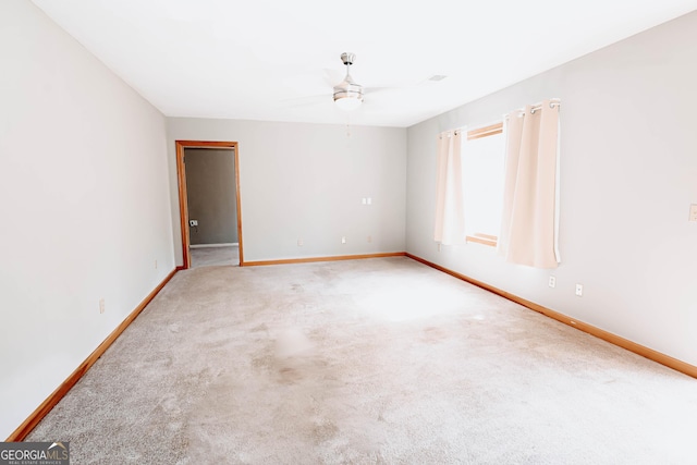 carpeted empty room with ceiling fan and baseboards