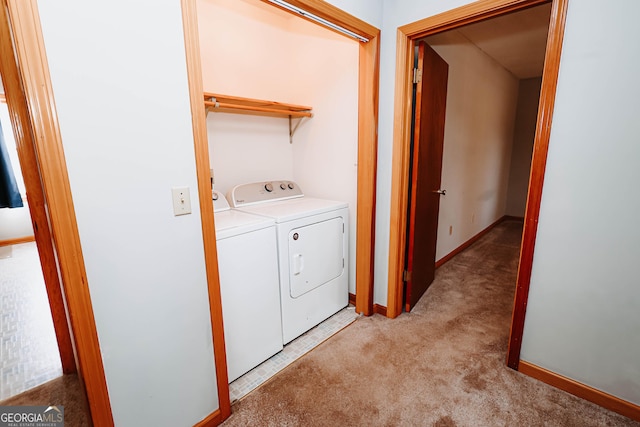 clothes washing area with light carpet, laundry area, washing machine and dryer, and baseboards