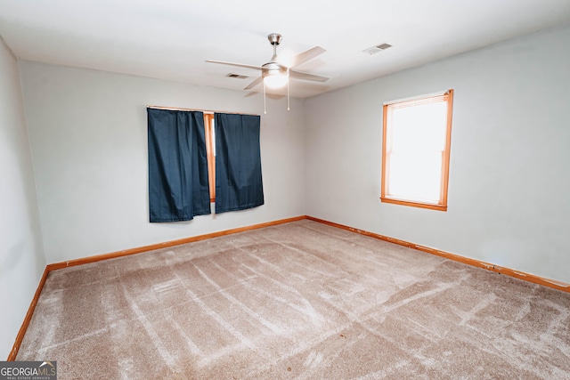 carpeted empty room featuring baseboards, visible vents, and ceiling fan