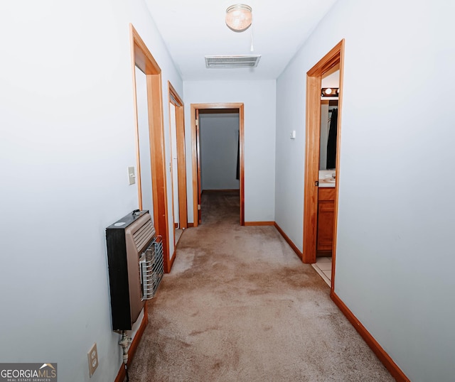 corridor featuring carpet flooring, visible vents, baseboards, and heating unit