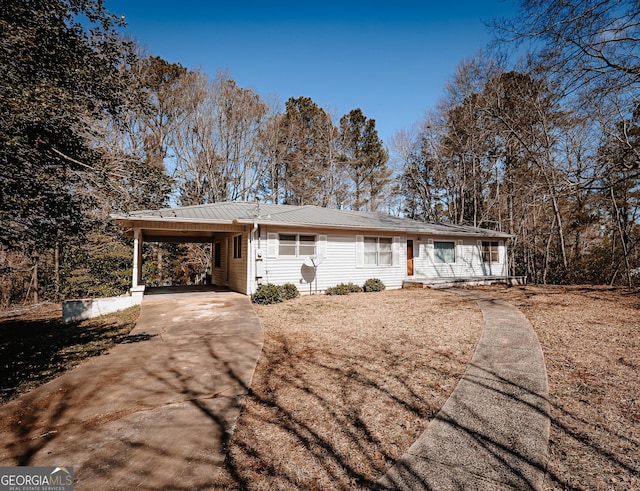 ranch-style house with a carport, metal roof, and concrete driveway