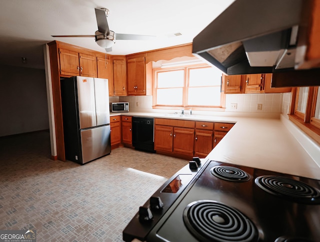 kitchen featuring under cabinet range hood, light countertops, appliances with stainless steel finishes, backsplash, and brown cabinets