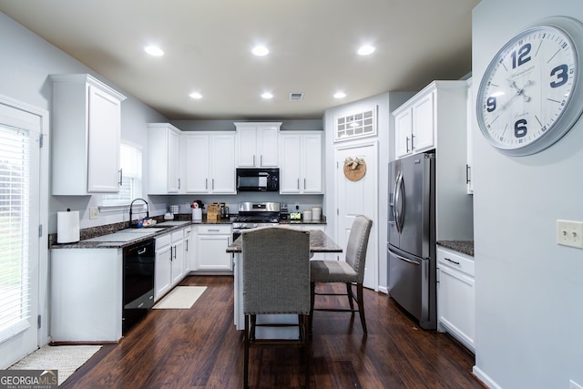 kitchen with visible vents, white cabinetry, a sink, black appliances, and a kitchen bar