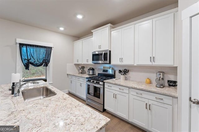 kitchen featuring stainless steel appliances, a sink, and white cabinets