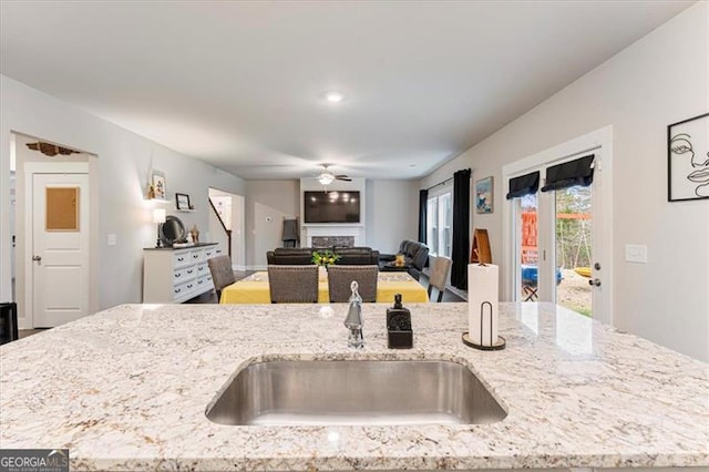 kitchen featuring light stone counters, a fireplace, and a sink