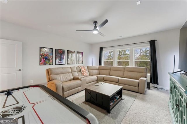 living room featuring baseboards, a ceiling fan, and light colored carpet