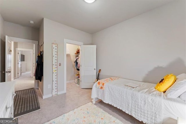 bedroom featuring light carpet, a spacious closet, baseboards, and a closet